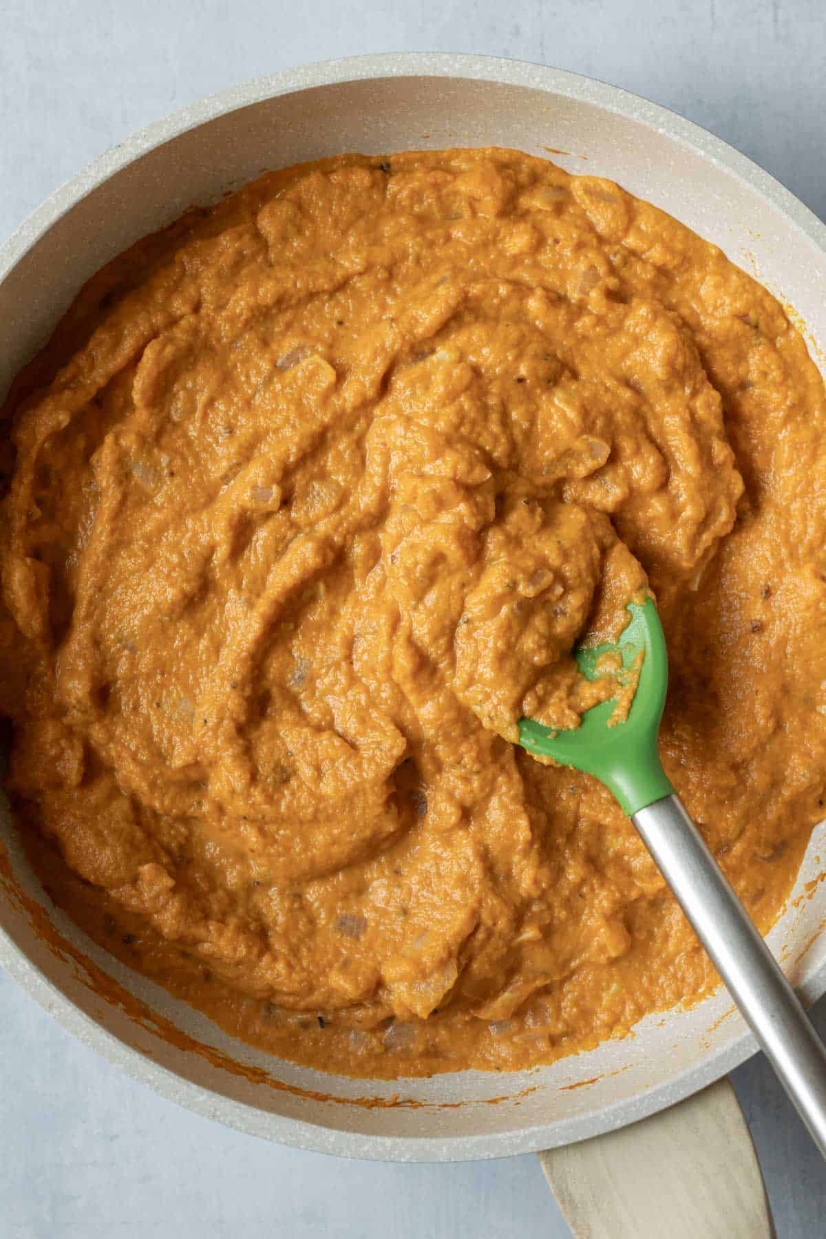 Chipotle pumpkin sauce in a skillet with a spoon.