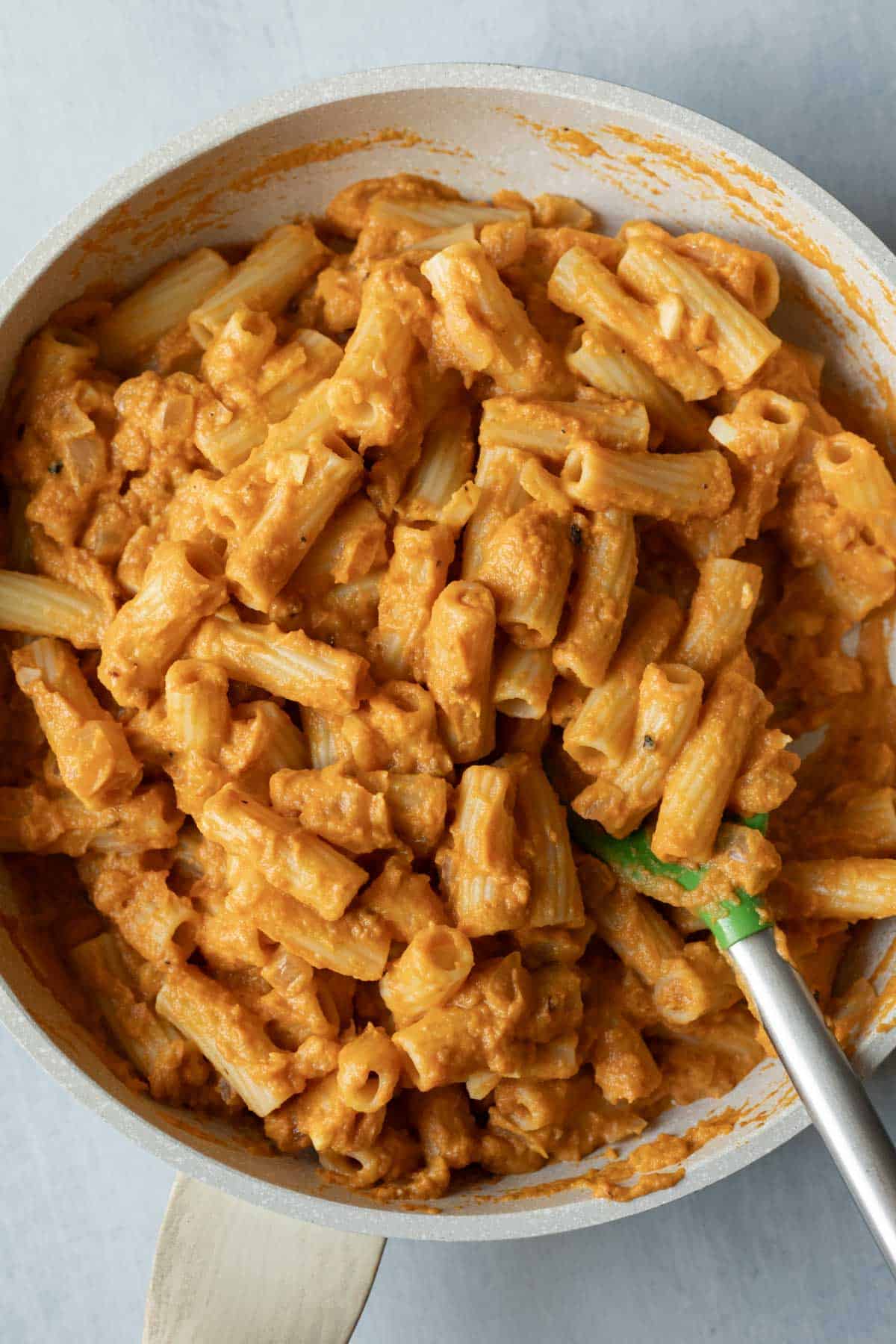 Pasta tossed with chipotle pumpkin sauce in a skillet with a spoon.