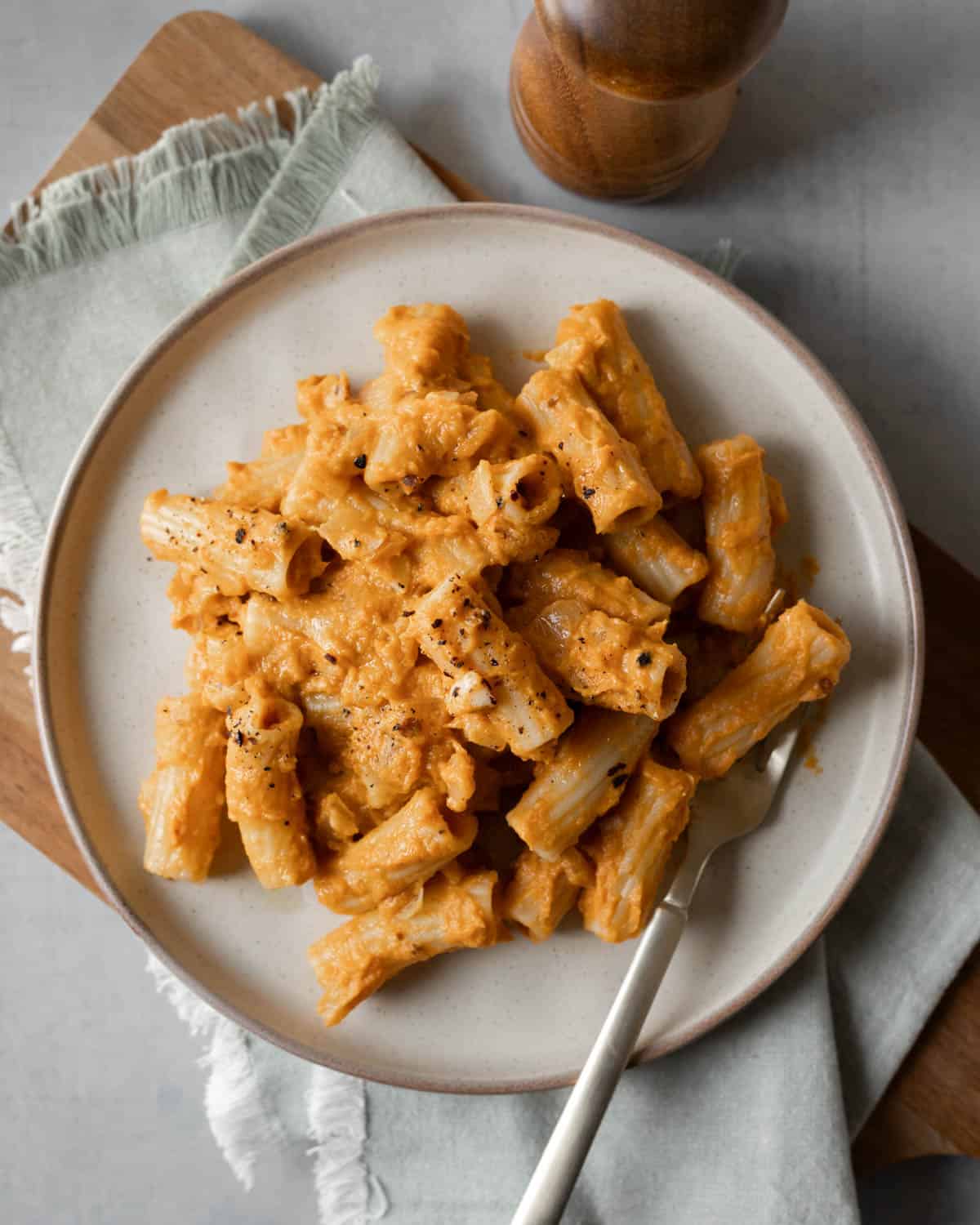 A serving of pumpkin chipotle pasta on a dish with a fork.