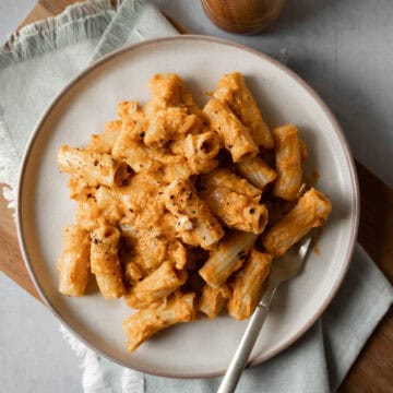 A serving of chipotle pumpkin pasta garnished with black pepper on a plate with a fork.