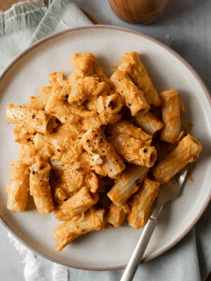 A serving of chipotle pumpkin pasta garnished with black pepper on a plate with a fork.