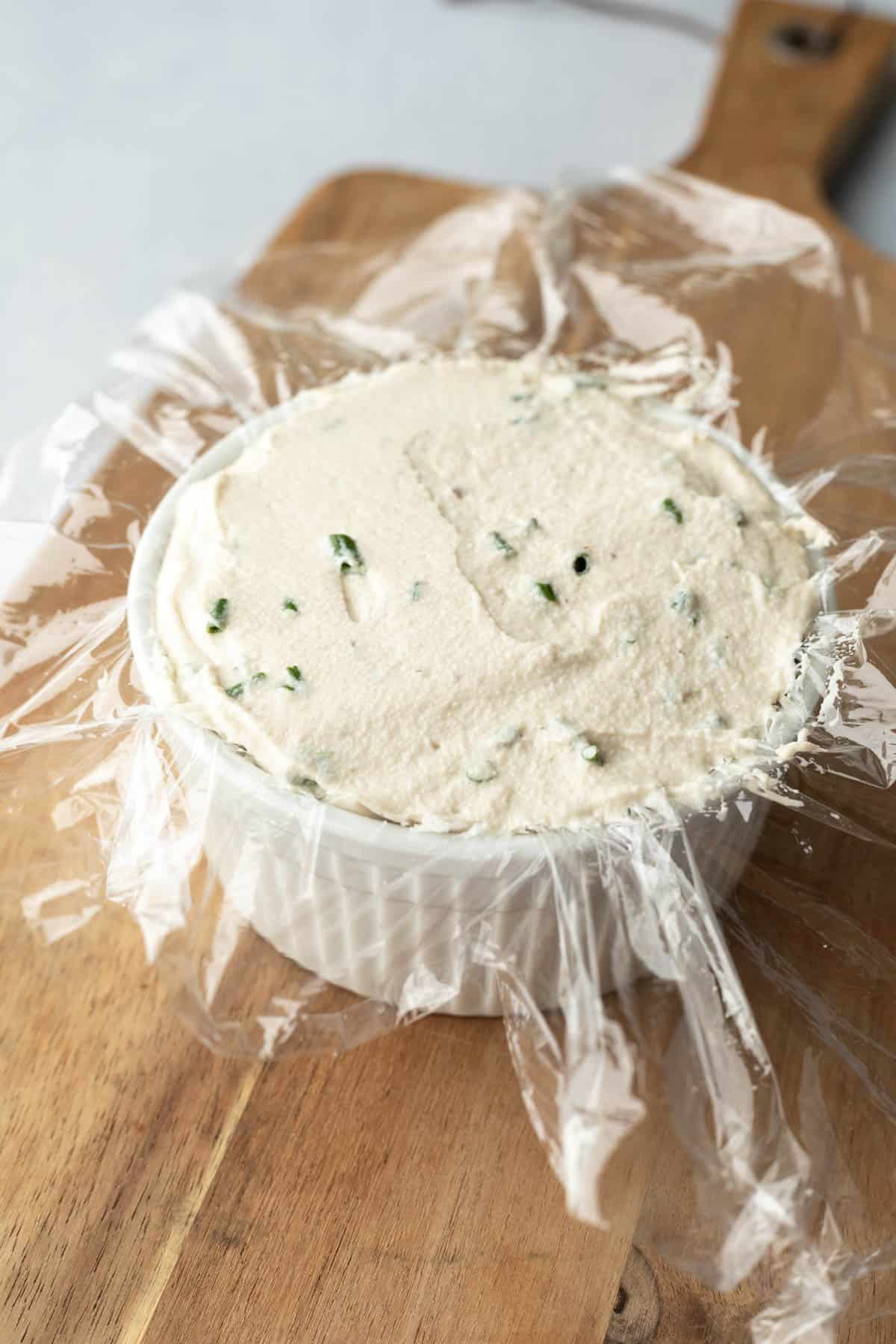 Herb cashew cheese spooned into a ramekin lined with plastic wrap or cheese cloth.