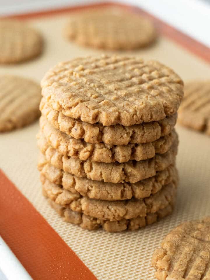 Seven corn cookies stacked on a baking mat.