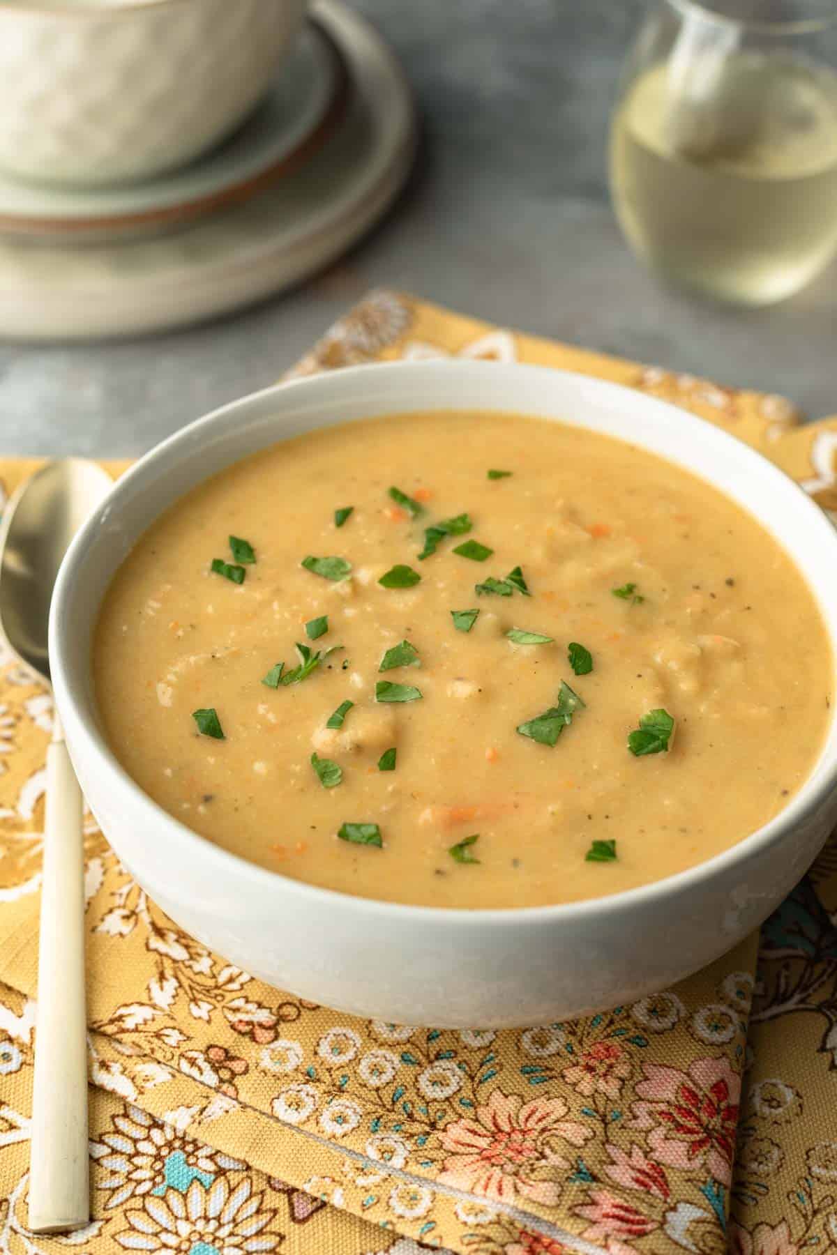 Potato soup in a white bowl with a spoon next to it. 