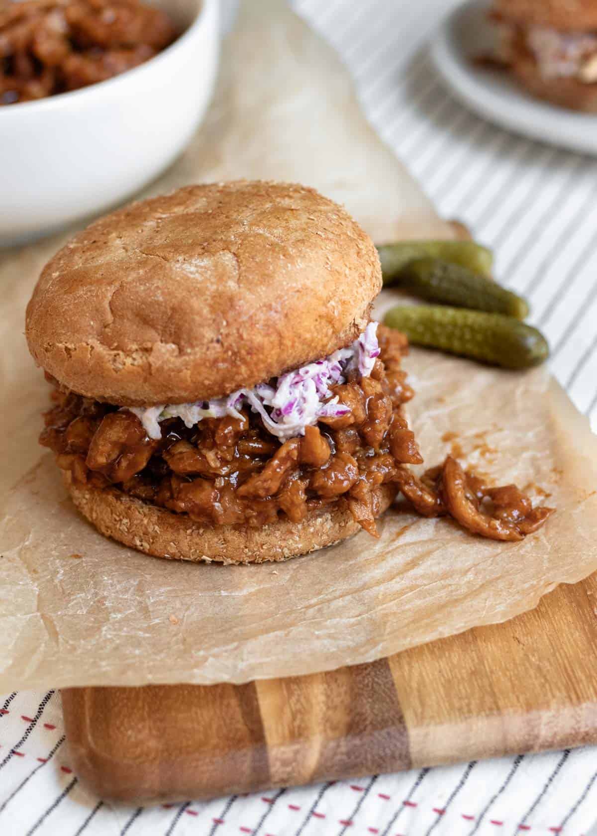 soy curl sandwich on a board with a bowl and plate in background.