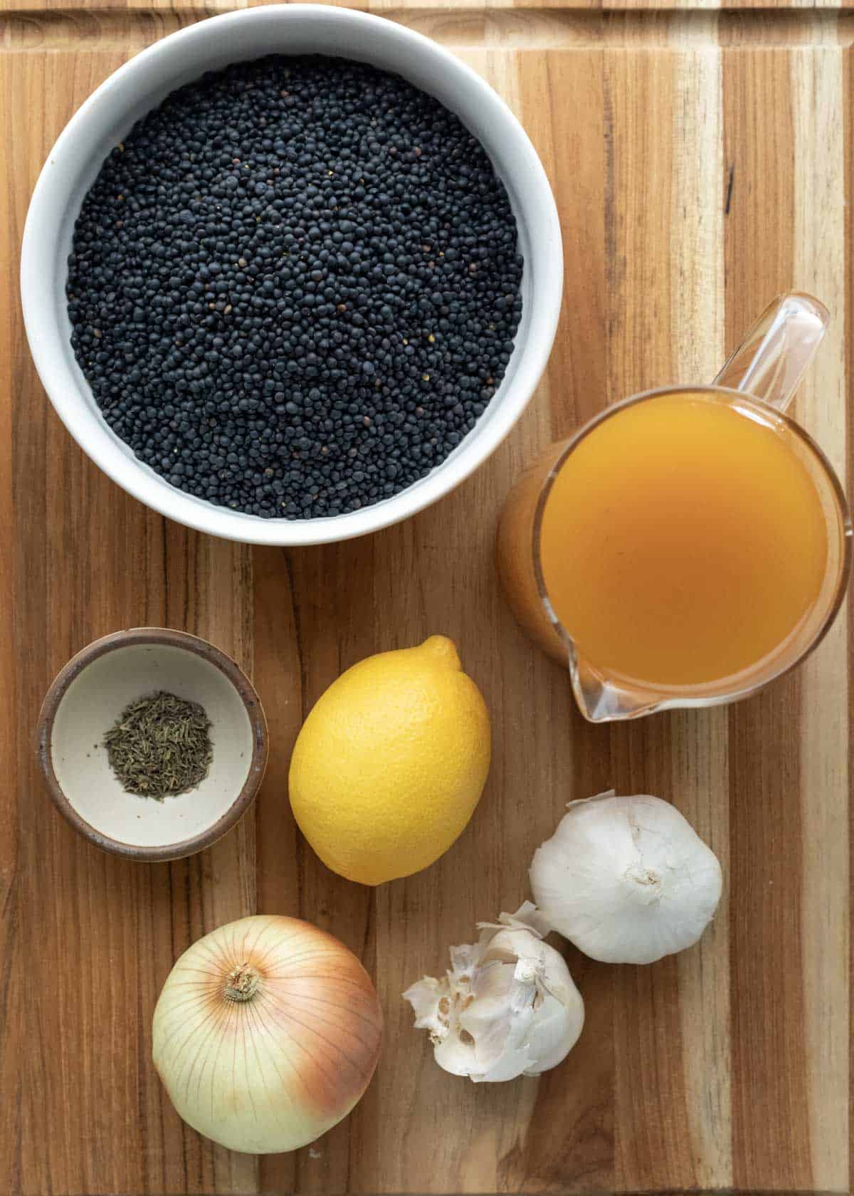 Ingredients for black lentils arranged on a wooden board.