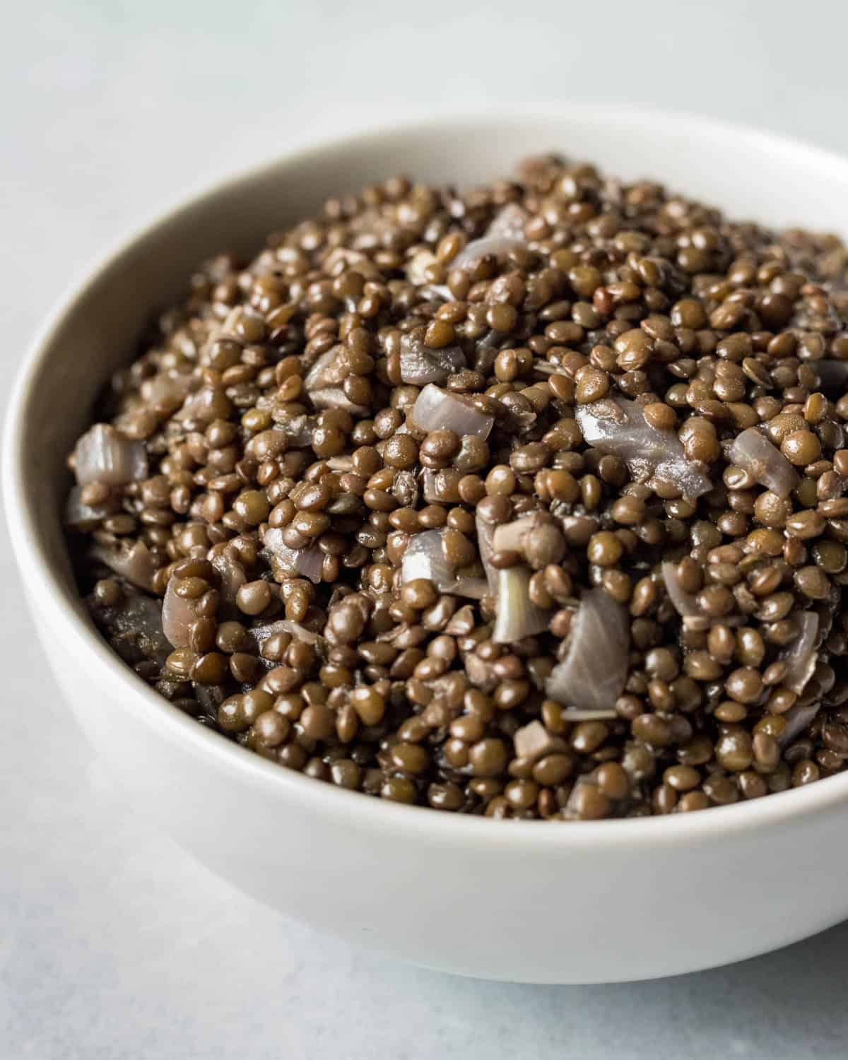 Cooked seasoned black lentils in a white bowl.