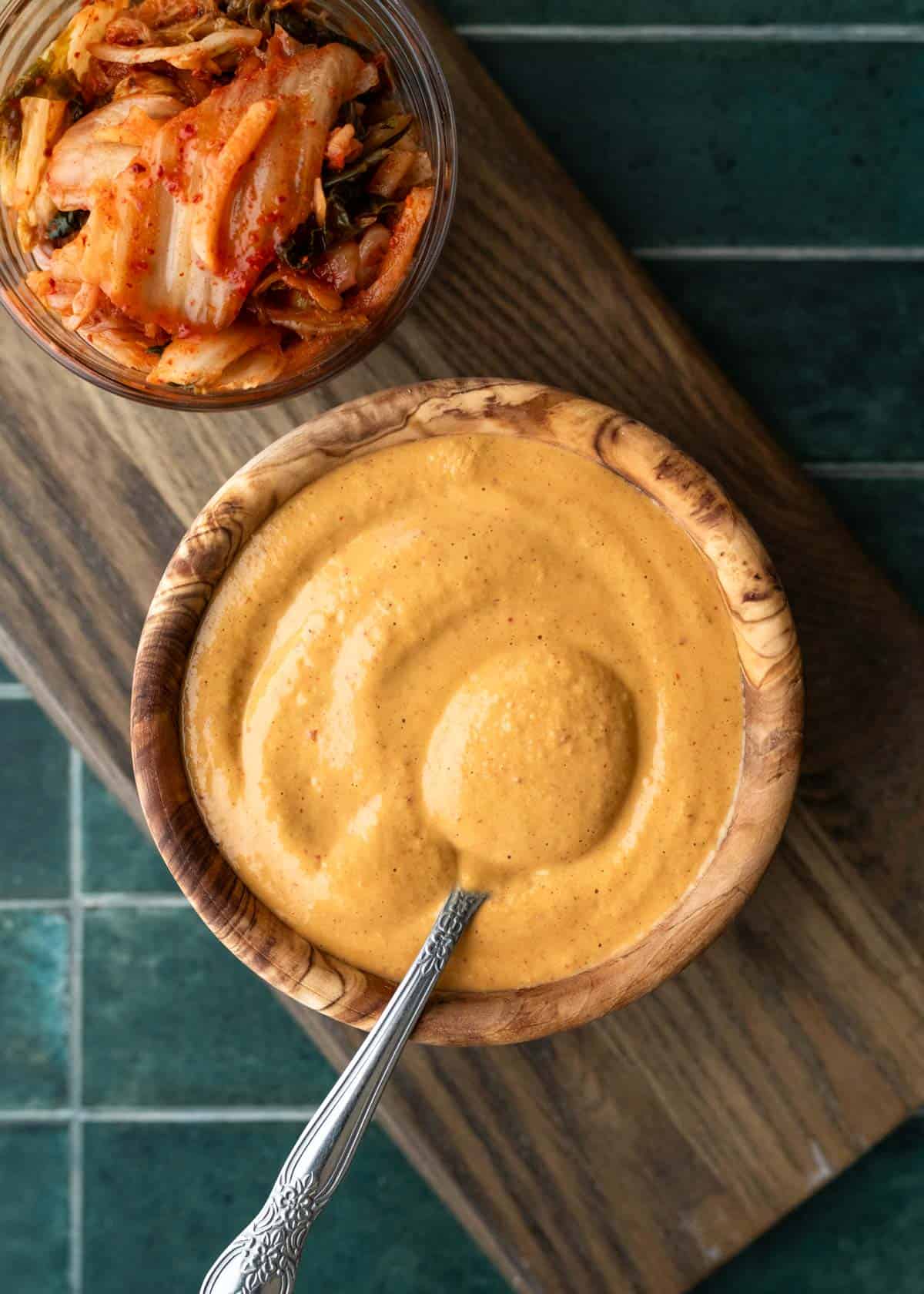 Creamy kimchi dressing in a wood bowl with a small bowl of kimchi nearby.