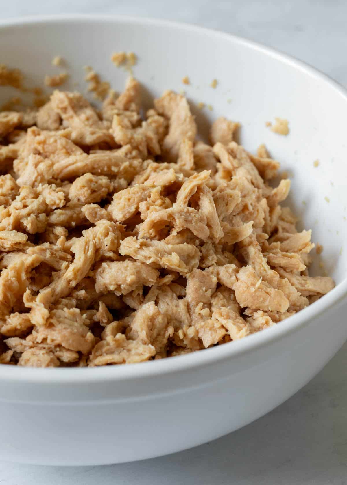 Rehydrated soy curls in a large bowl ready to be tossed with BBQ sauce.