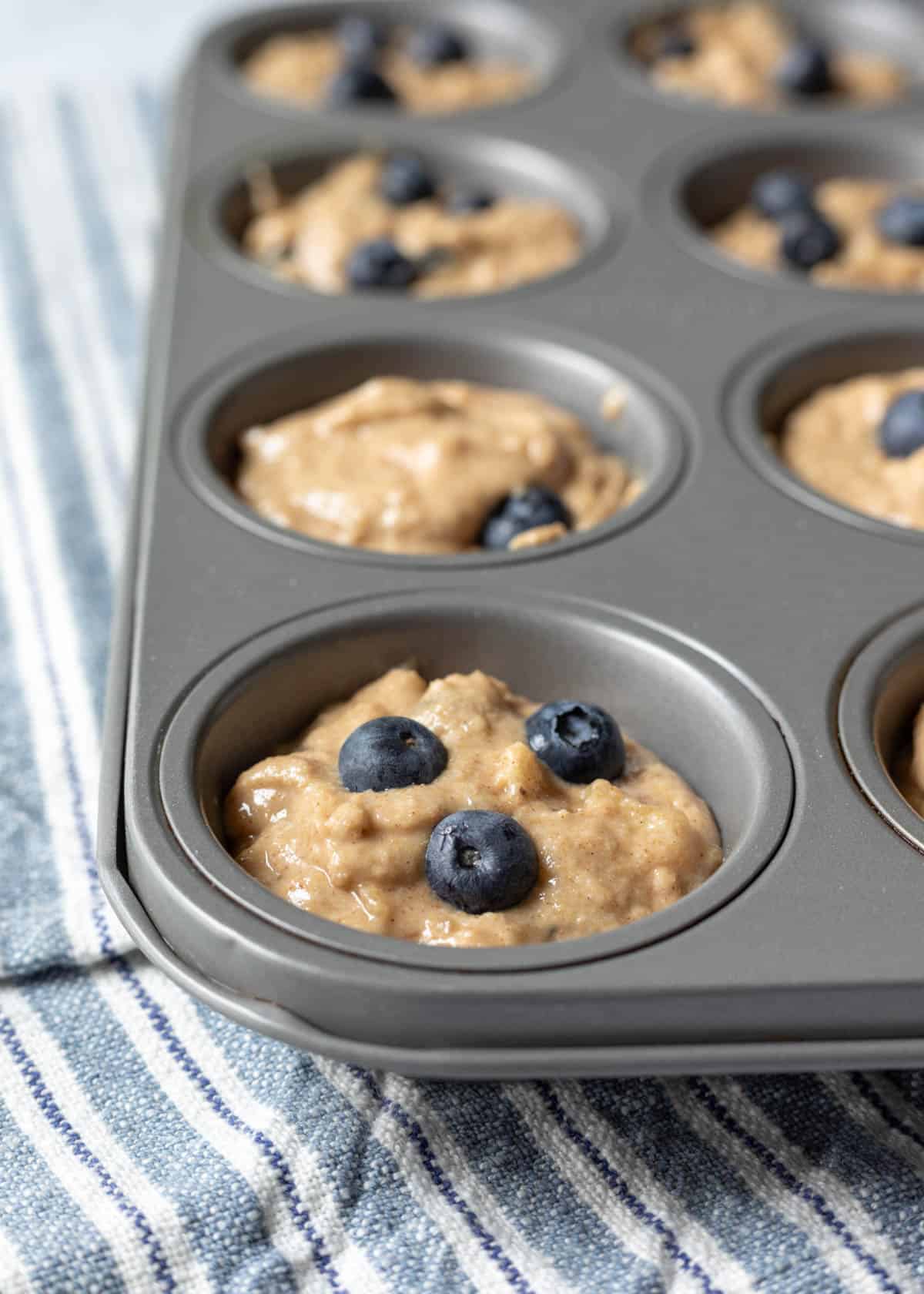 Blueberry banana muffin batter in a muffin pan ready to be baked.