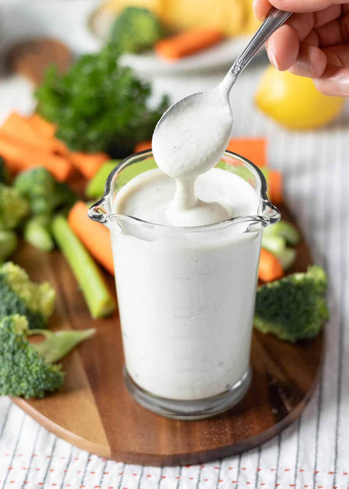 Dipping a spoon into thick and creamy vegan ranch dressing in a jar.