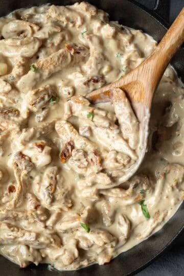 Soy curls coated in a creamy sauce inside a skillet.