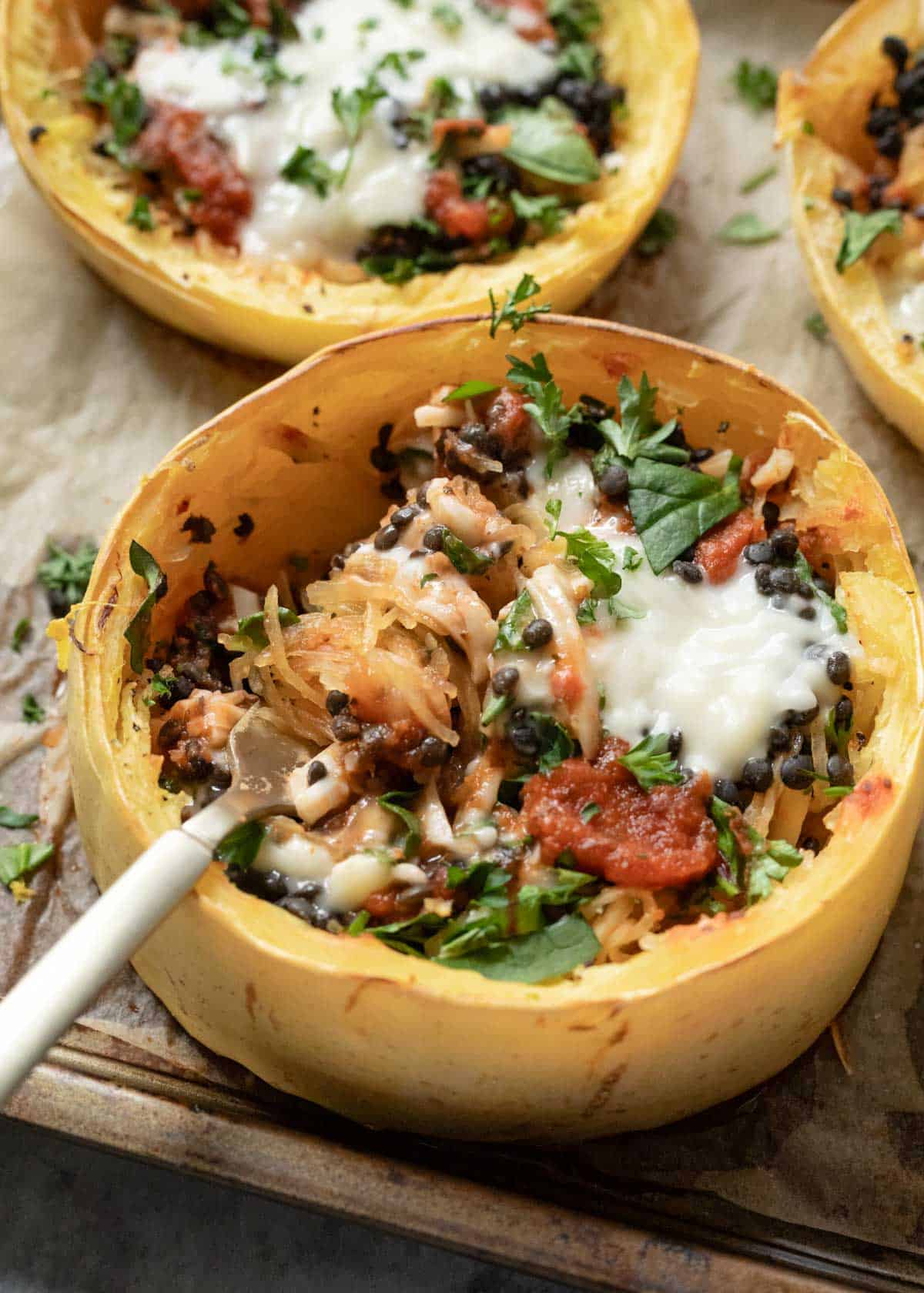 A stuffed spaghetti squash round with a fork scooping up a bite.