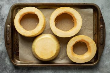 Spaghetti squash rings on a parchment-lined baking sheet before cooking.