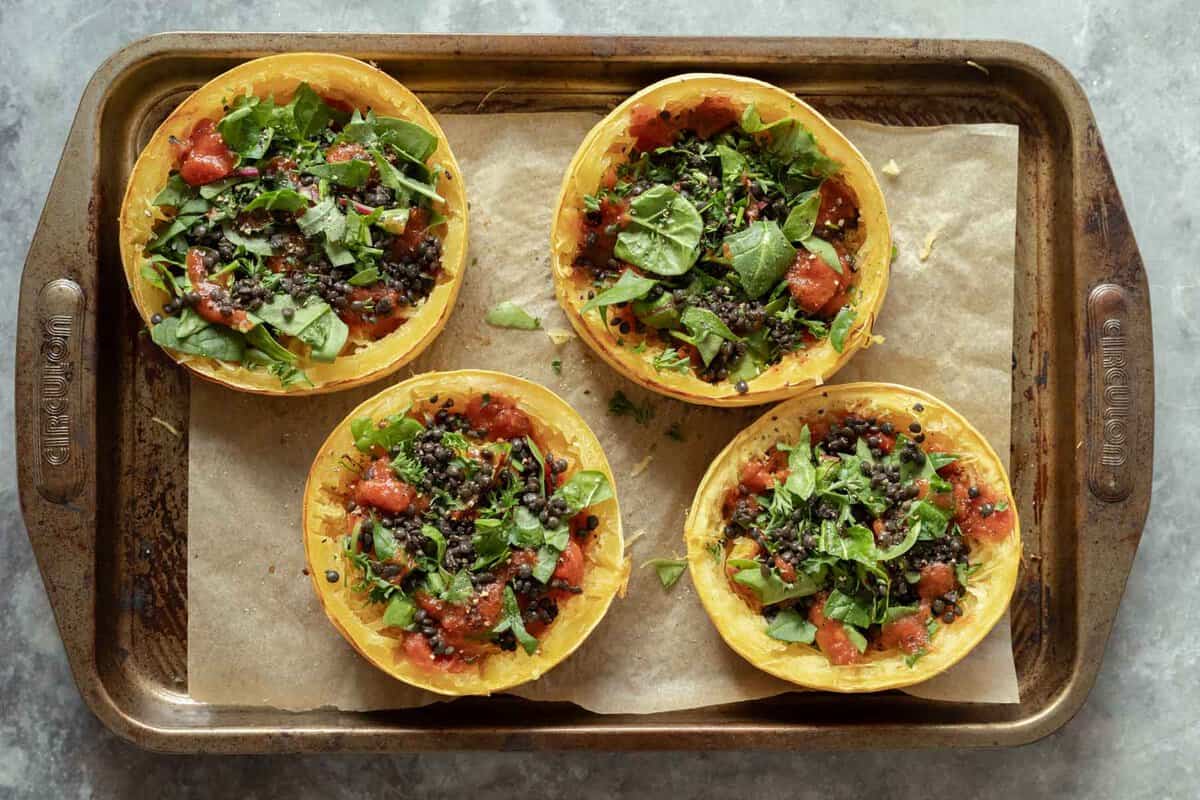 Stuffed spaghetti squash rings on a baking sheet after adding the filling.