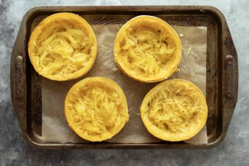 Spaghetti squash rings on a parchment-lined baking sheet after cooking before adding the filling.