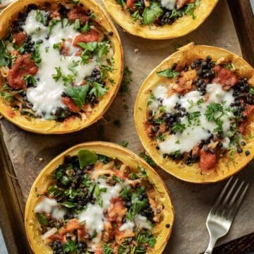 Stuffed vegan spaghetti squash rings on a wooden board with a fork next to them.