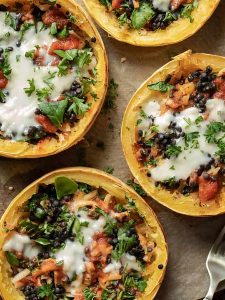 Stuffed vegan spaghetti squash rings on a wooden board with a fork next to them.