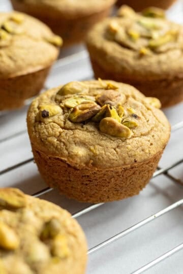 Vegan pistachio muffins on a cooling rack.