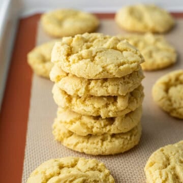 A stack of crispy corn flour cookies on a baking mat.