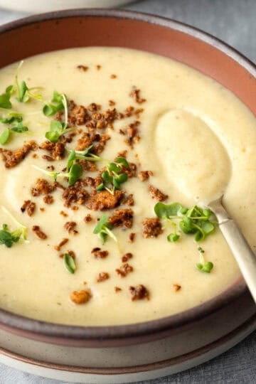 A bowl of creamy cauliflower soup topped with crumbled vegan bacon bits.