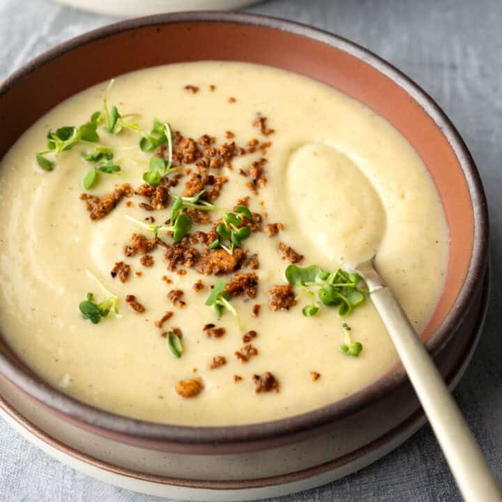 A bowl of creamy cauliflower soup topped with crumbled vegan bacon bits.