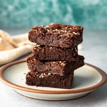 A stack of four fudgy buckwheat brownies on a small plate.