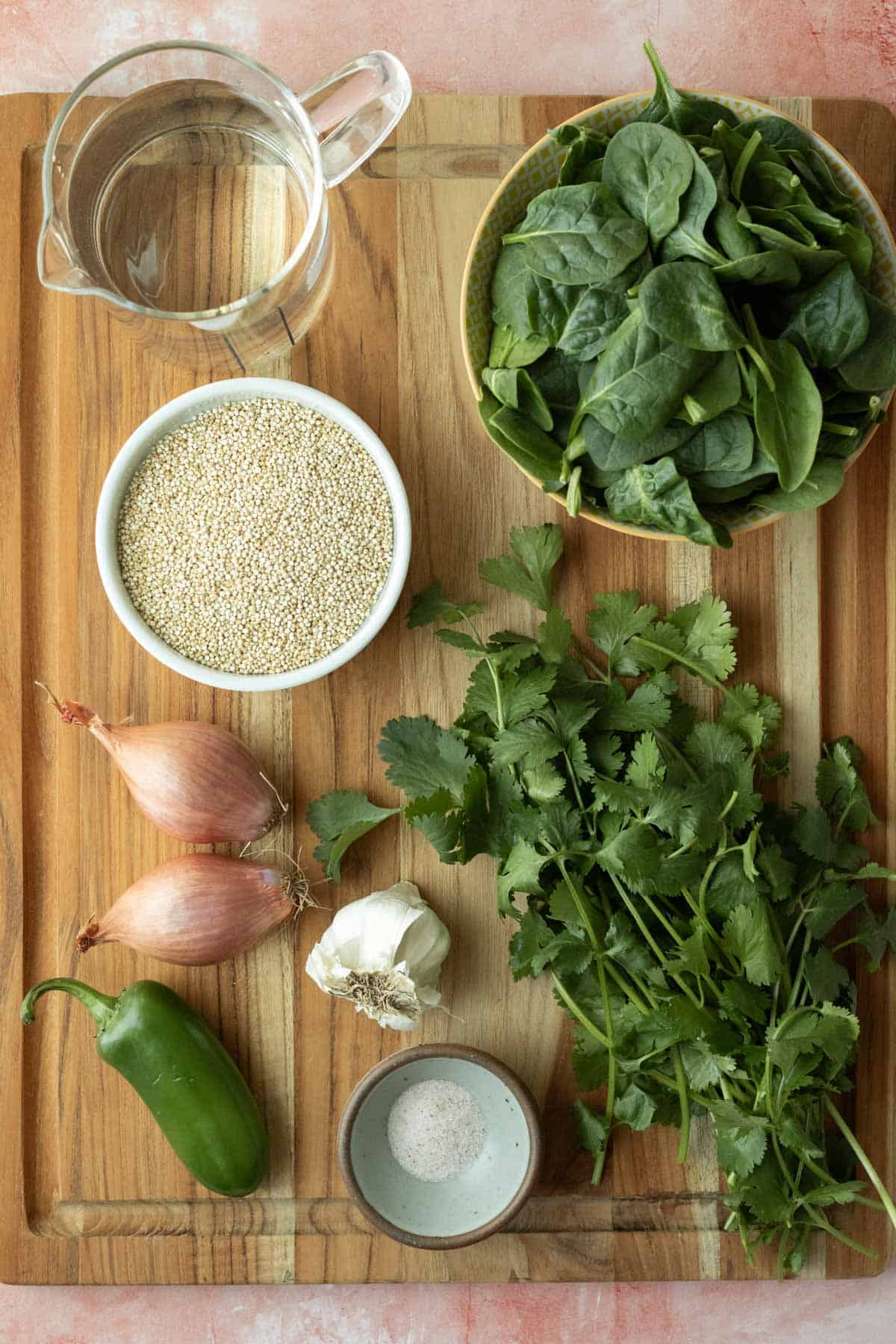 The ingredients needed for green quinoa set out on a wood cutting board.