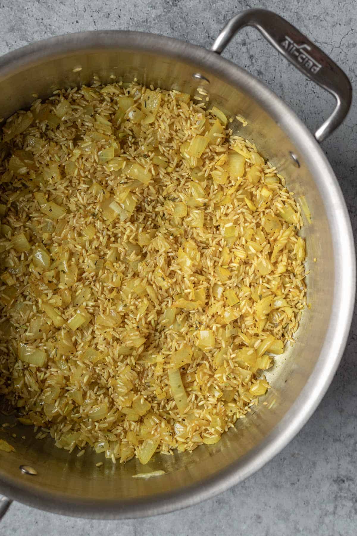 Toasting aromatics and brown rice in oil.