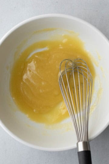 Whisking together wet ingredients in a mixing bowl.