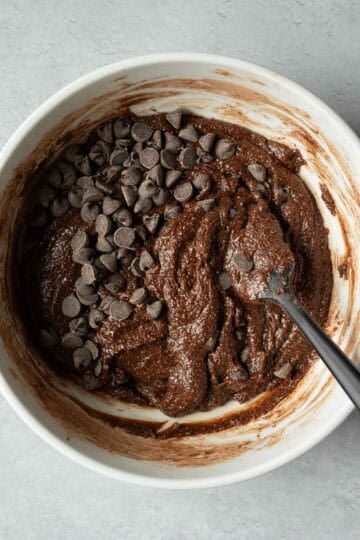 Stirring brownie batter and folding in chocolate chips.