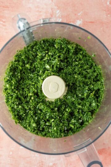 Finely chopped spinach, cilantro, and shallot inside a food processor.