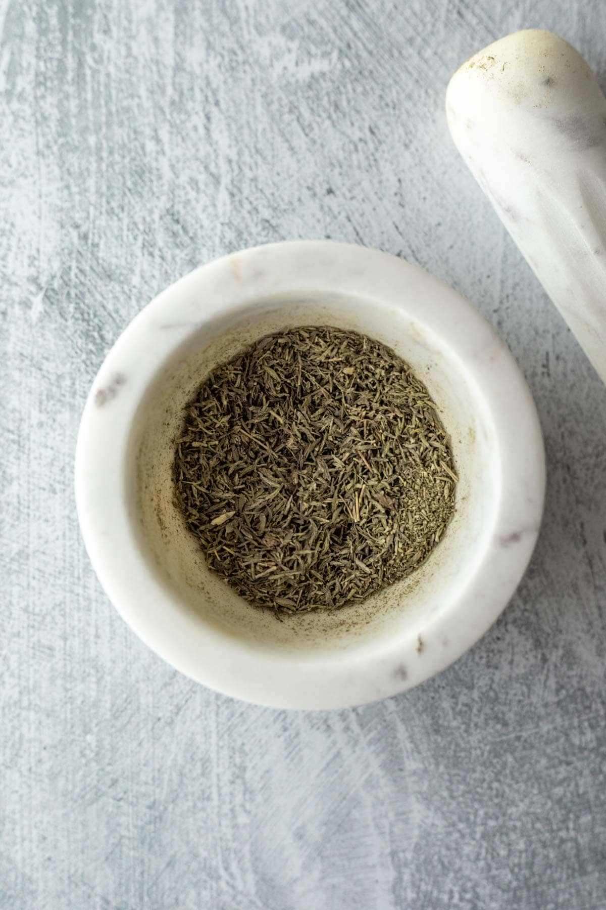 Grinding thyme with a mortar and pestle.