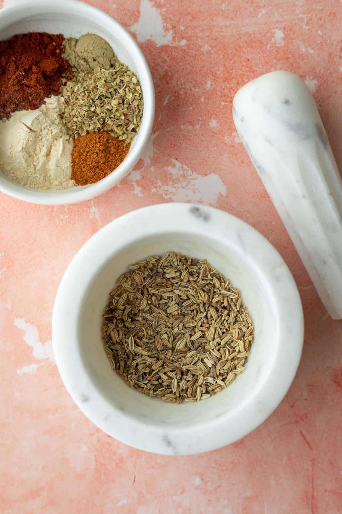 Grinding fennel seeds with a mortar and pestle.