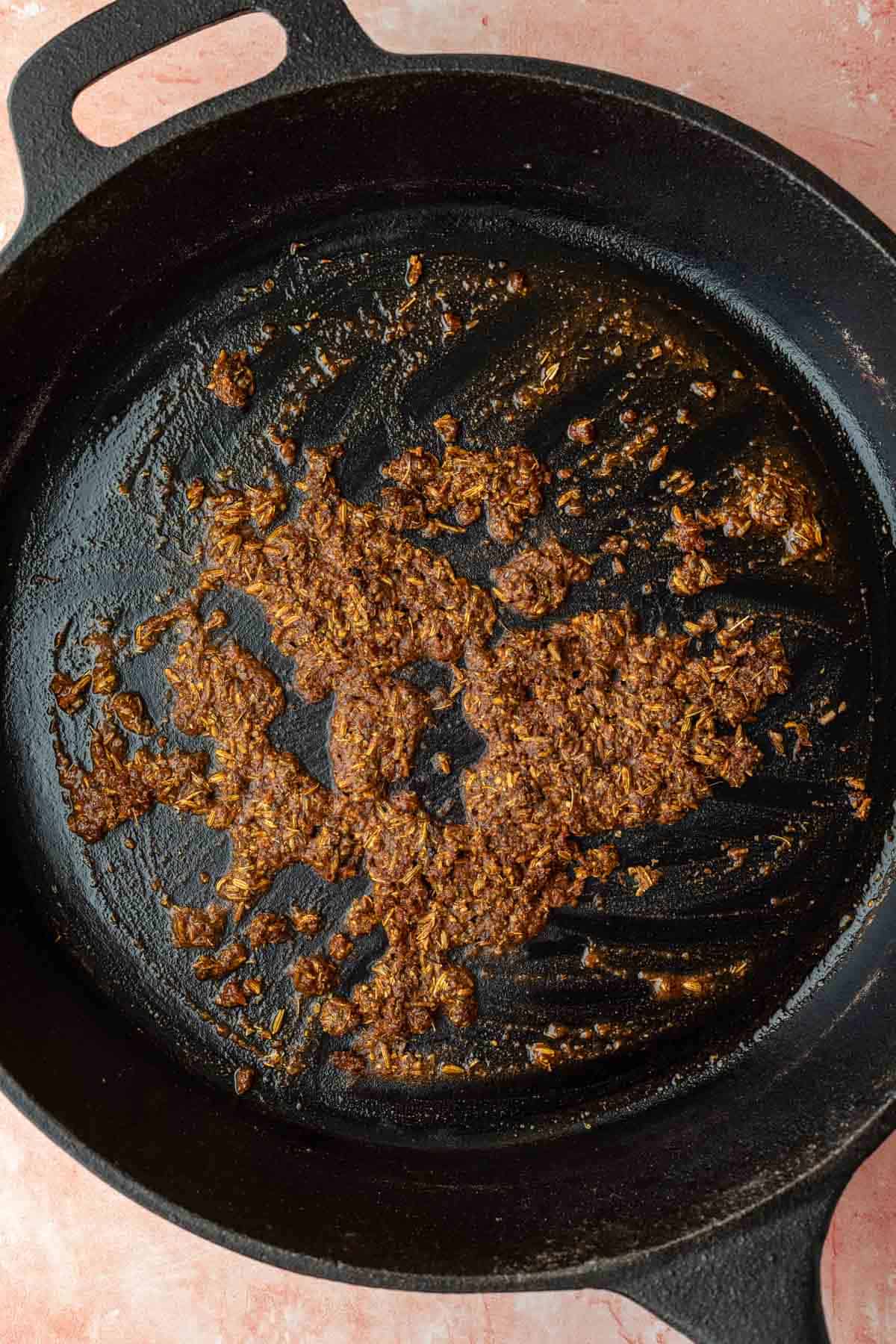 Heating herbs and spices in oil in a cast iron skillet.