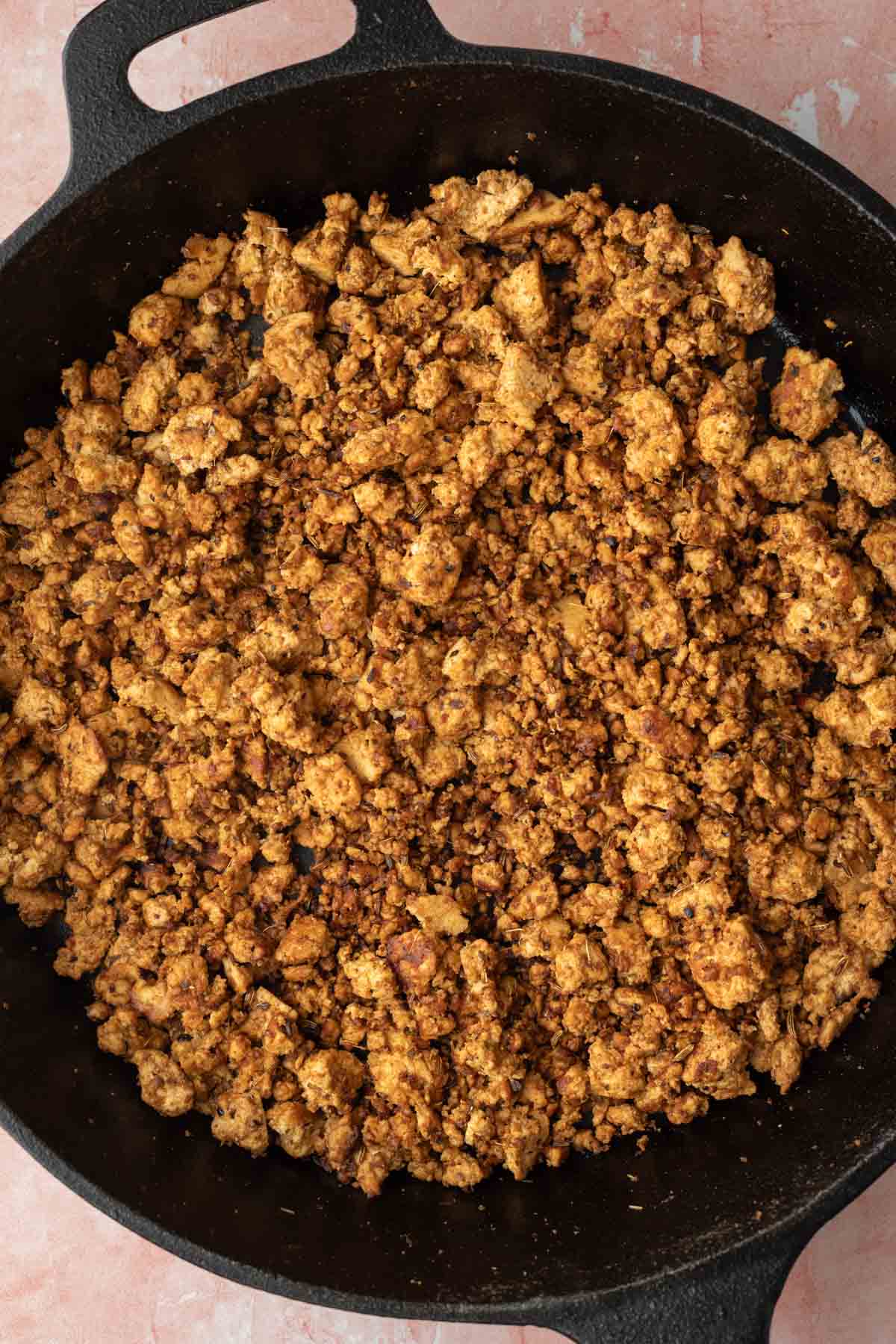 Browned tofu crumbles in a skillet.