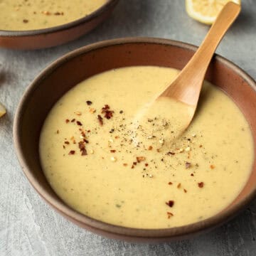 A spoon resting in a bowl of creamy red lentil soup.
