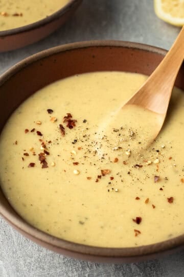 A spoon resting in a bowl of creamy red lentil soup.