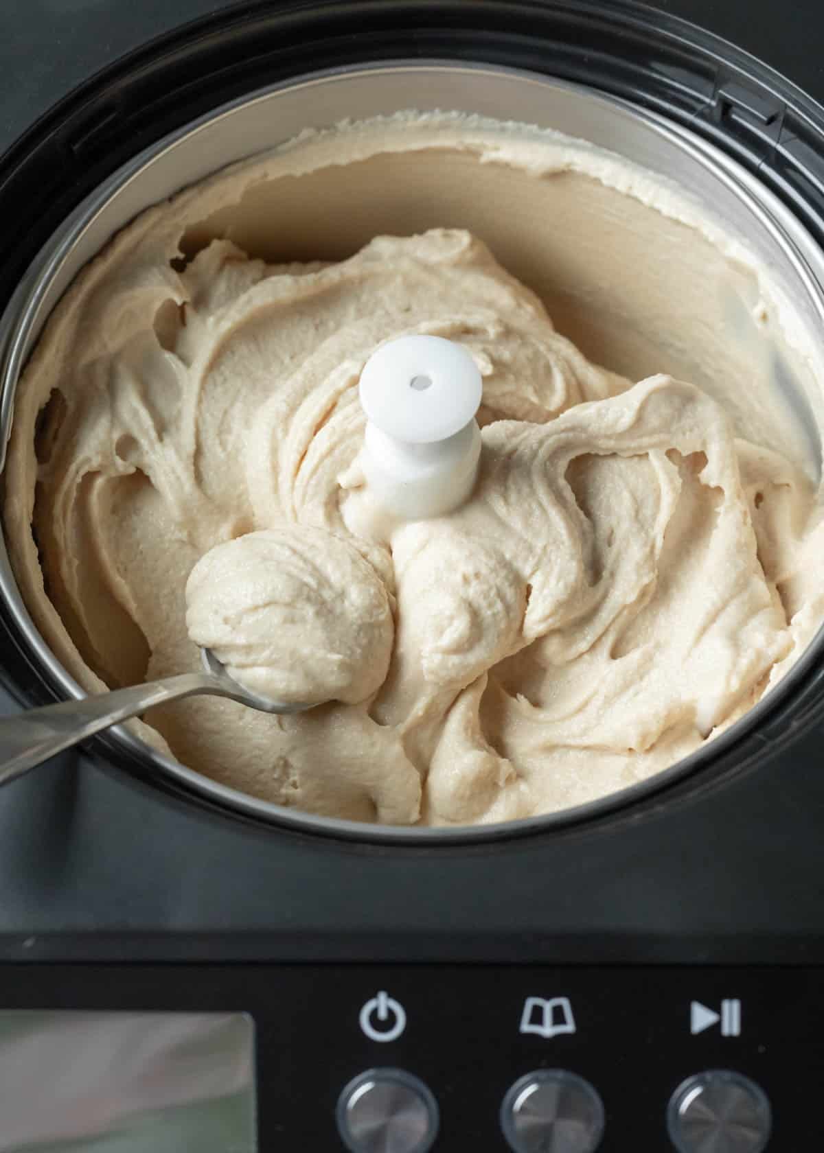 Looking inside an ice cream maker at vegan ice cream with soft-serve consistency.