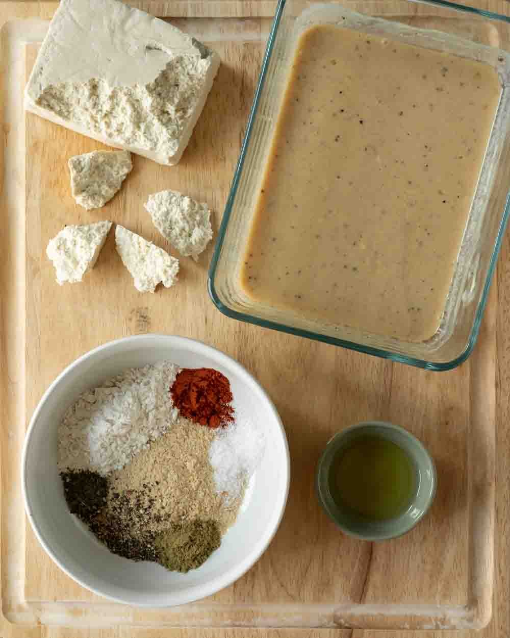Ingredients needed to make tofu nuggets laid out on a wood cutting board.