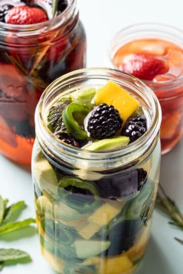 A jar of pickled mango and blackberries with cucumber and jalapeno.