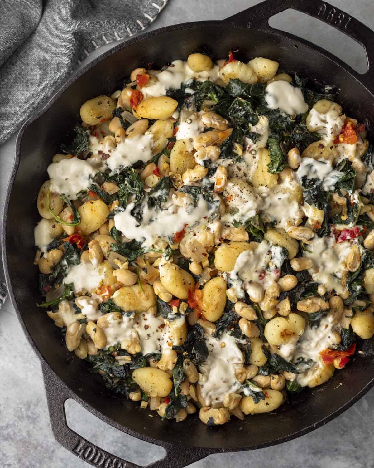 Overhead view of skillet filled with Italian beans and greens and gnocchi.