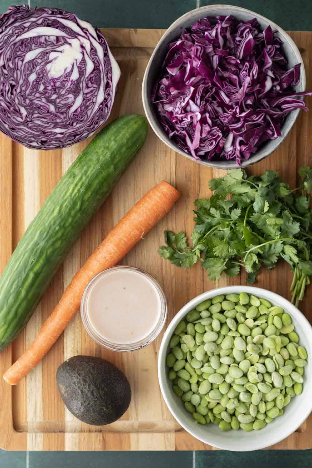 Edamame salad ingredients laid out on a wood cutting board.