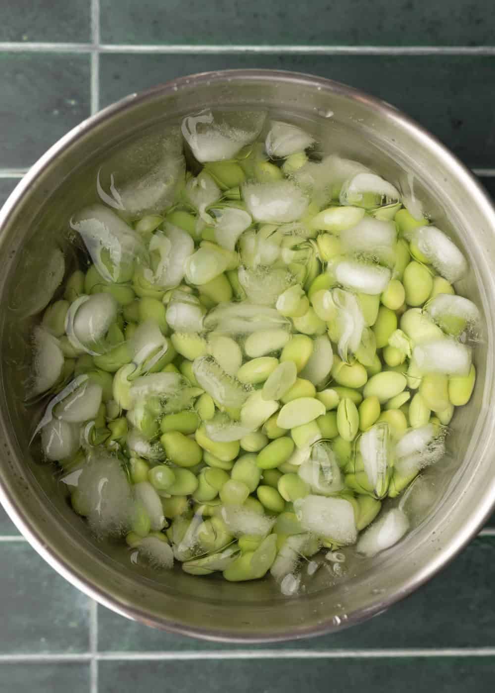 Cooling cooked edamame in a bowl of ice water.
