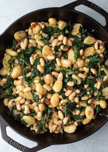 White beans and greens with gnocchi in a skillet.