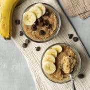 Overhead view of two microwave banana bread mug cakes topped with sliced banana.