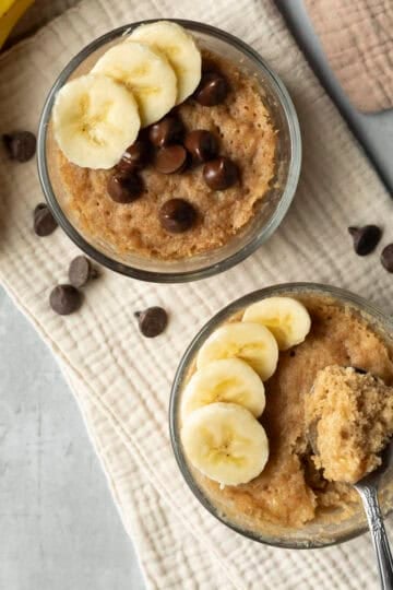 Overhead view of two microwave banana bread mug cakes topped with sliced banana.
