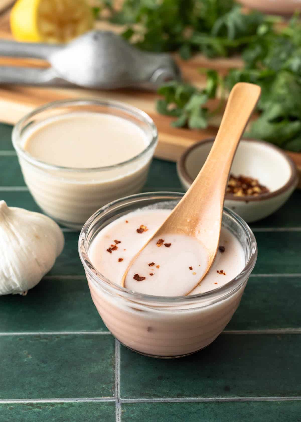 A small glass container filled with pale pink ume vinegar dressing.
