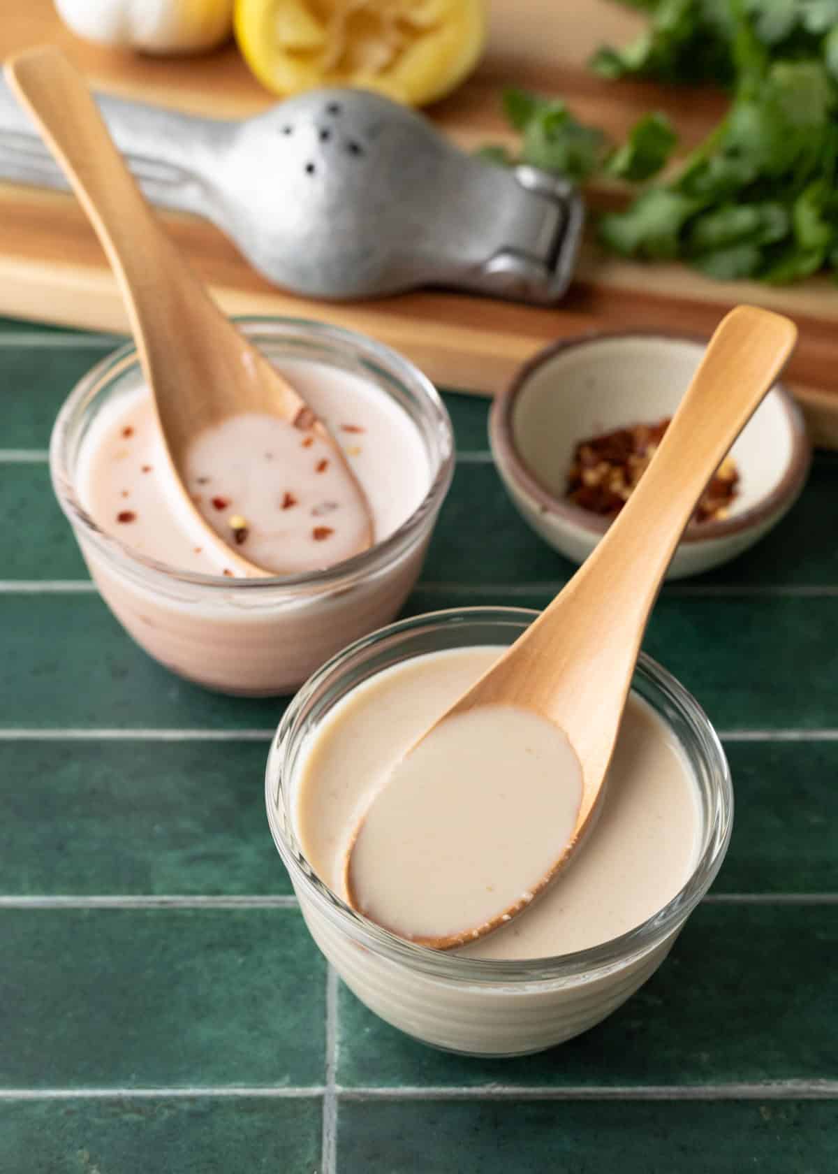 Close up view of the tahini-ume vinegar dressing with a spoon scooping it up.