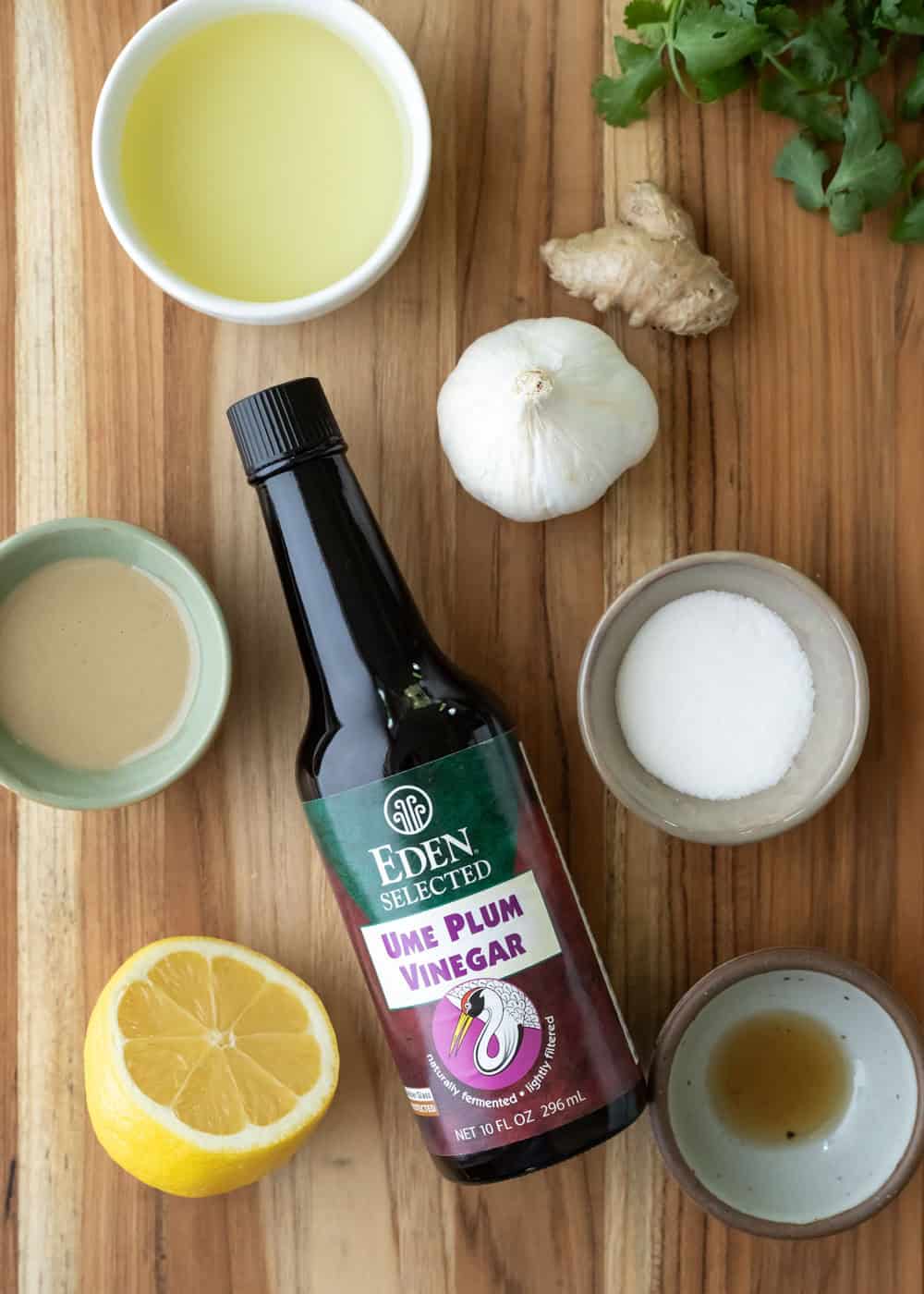 The six ingredients needed to make ume plum vinegar dressing on a wood board.